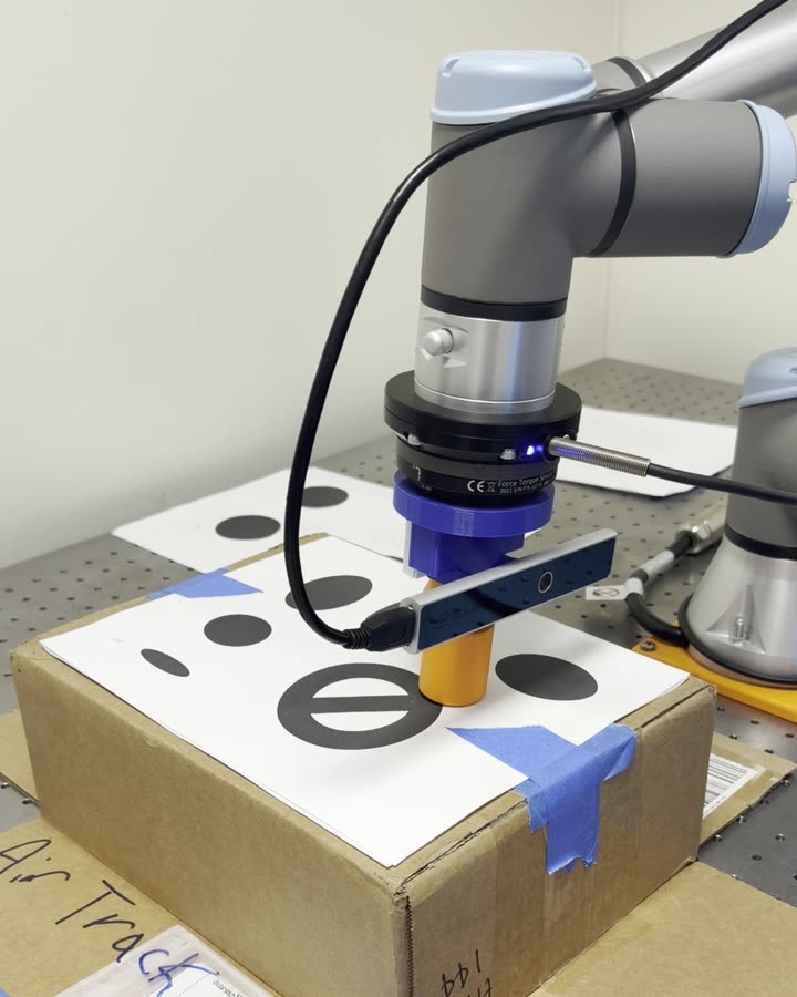 Robot arm tracing a path on a box lid